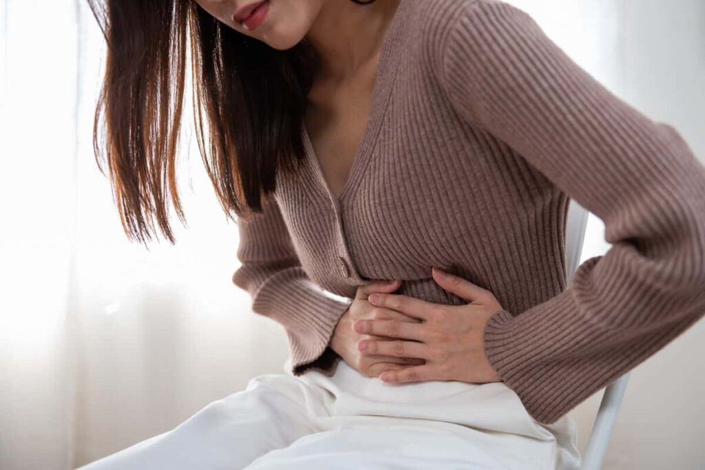 Young Woman with abdominal pain holding abdomen